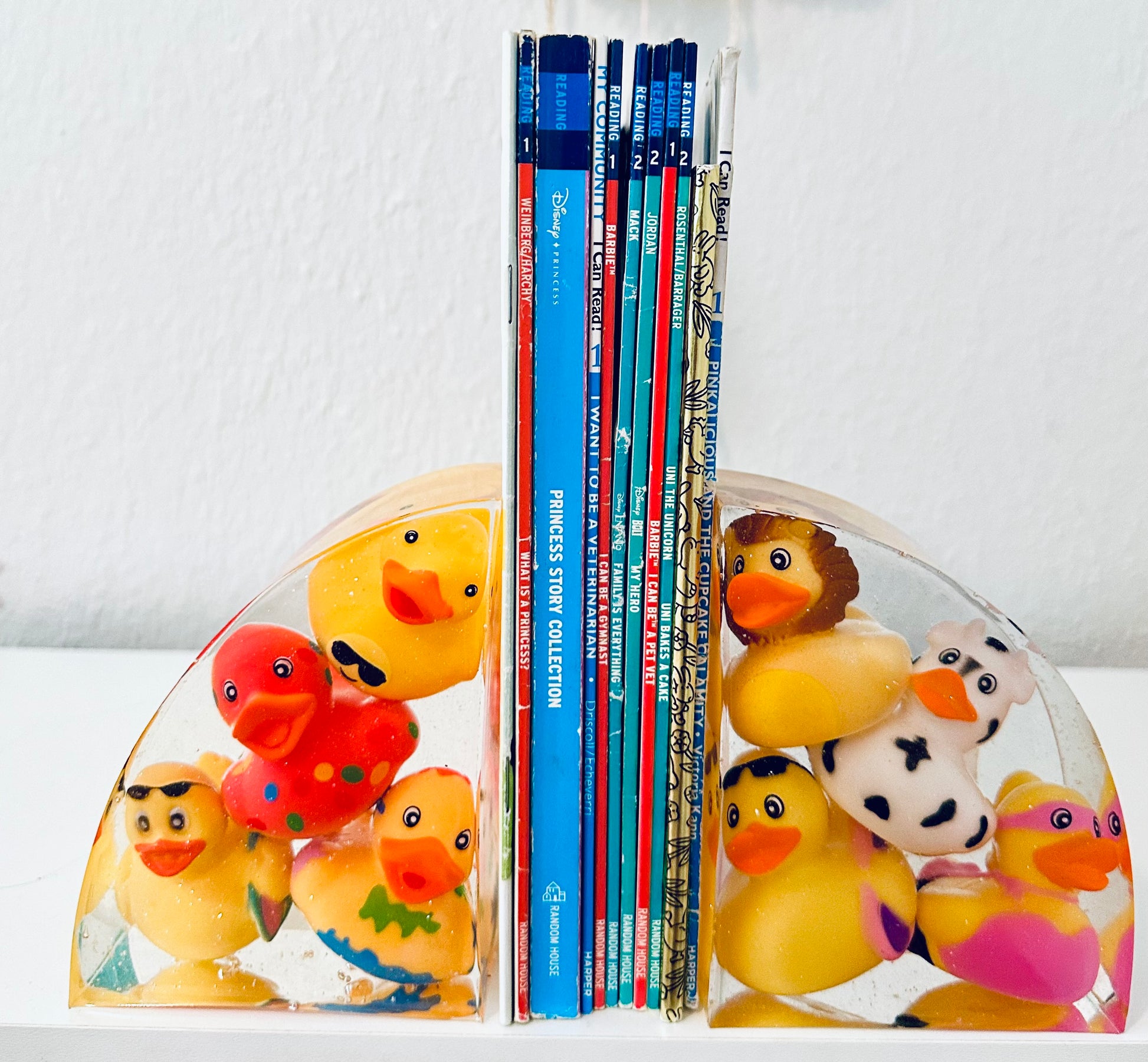 Close-up of handmade resin bookends with four yellow plastic rubber ducks and a touch of glitter.